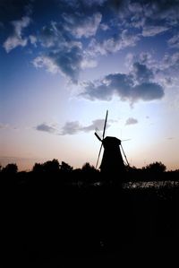 Silhouette windmill on field against sky during sunset