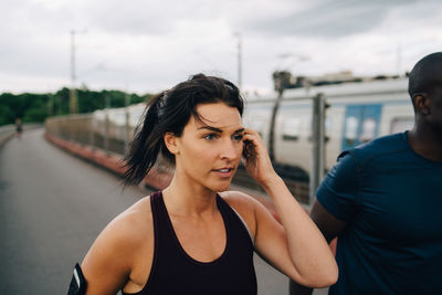 Young female athlete looking away while jogging with male friend on footbridge