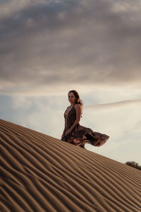 Low angle portrait of woman standing against sky