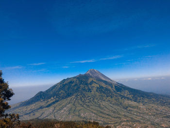 Scenic view of volcanic mountain against blue sky