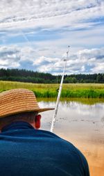 Person holding hat against sky