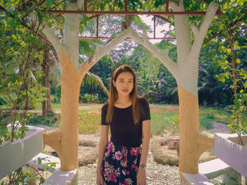 Portrait of young woman standing against plants