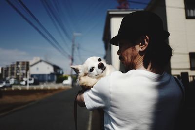 Man carrying dog by street in city