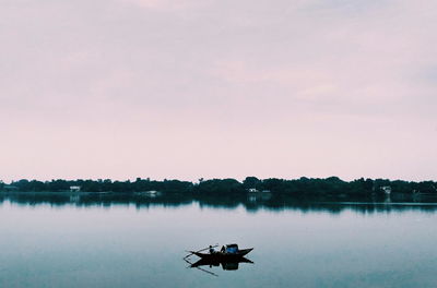 Silhouette of boat in lake against sky during sunset