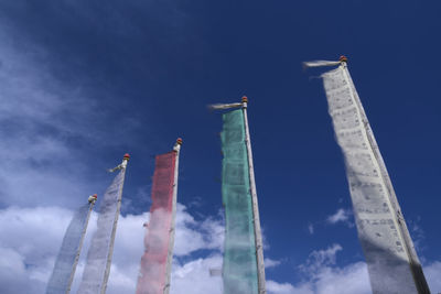 Low angle view of colorful prayer flags against blue sky