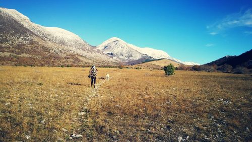 Full length of man walking on mountain against blue sky