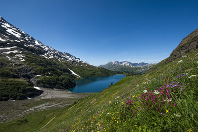 Scenic view of lake and mountains against blue sky