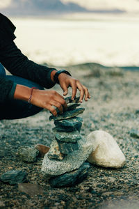 Low section of man stacking stones