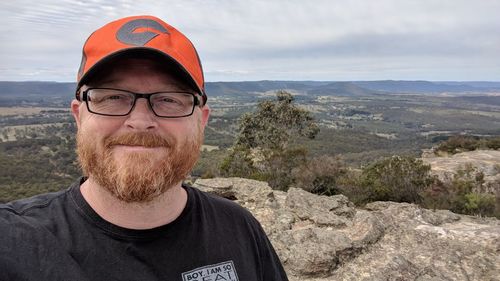 Portrait of smiling man standing by tree against sky