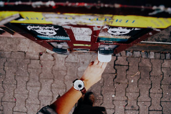 Cropped image of man using gumball machine on footpath in city