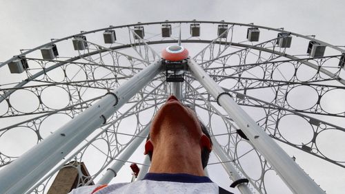 Low angle view of man on metallic structure against sky