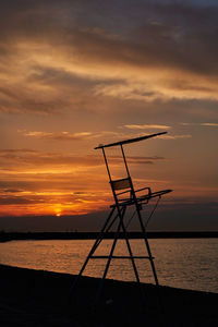 Silhouette poles on beach against sky during sunset