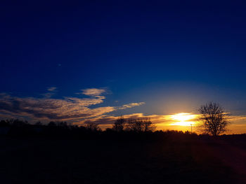 Scenic view of silhouette landscape against blue sky at sunset