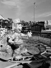 Statue by railroad tracks against sky