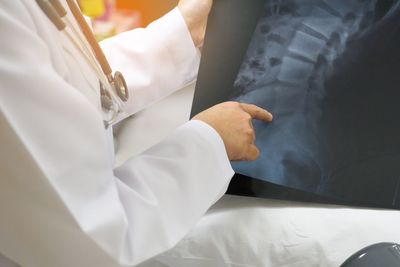 Midsection of doctor holding x-ray image in hospital