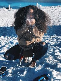 Young woman playing on snow field during winter