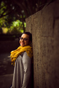 Portrait of smiling young woman standing against wall