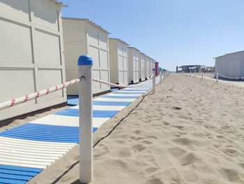 Hooded beach chairs on sand against clear sky