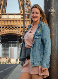 Portrait of young woman standing against building