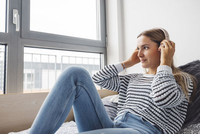 Young woman sitting on sofa at home