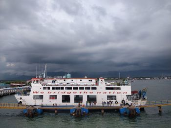 Boats moored at harbor against sky