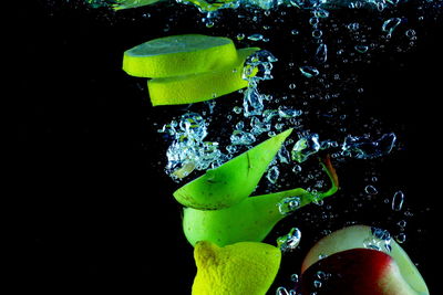 Close-up of green fruit on water against black background
