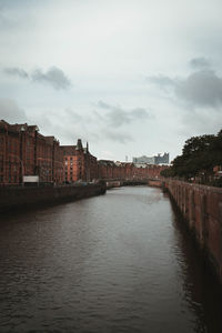 Bridge over river by buildings in city against sky