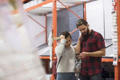 Couple using smart phone while standing in hardware store
