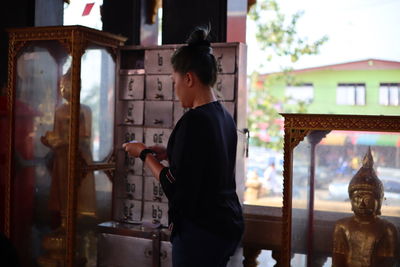 Side view of woman standing in buddha temple