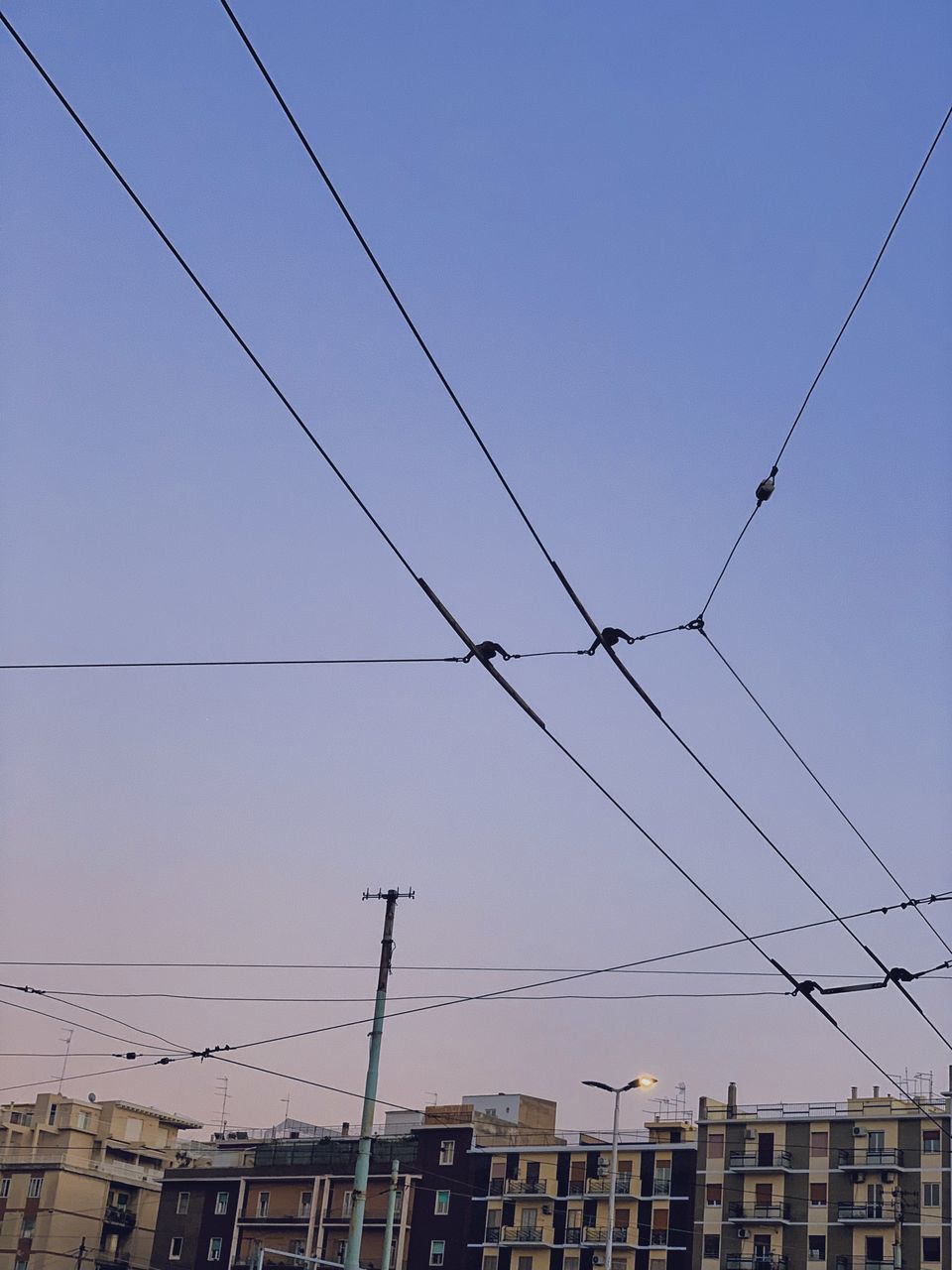 LOW ANGLE VIEW OF CABLES AGAINST BUILDINGS IN CITY