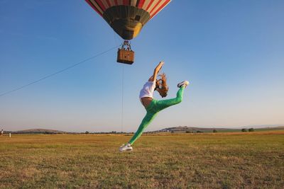  girl  jumping to catch hot air balloon on field against sky