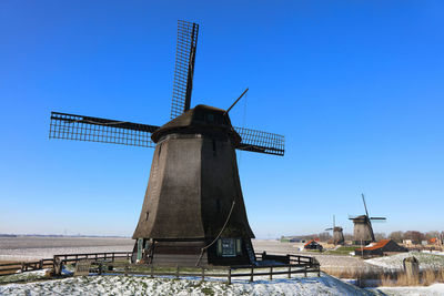 Traditional windmill on field against clear blue sky