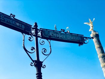 Low angle view of cross sign against clear blue sky