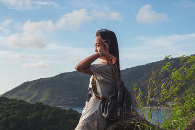 Young woman standing on mountain against sky