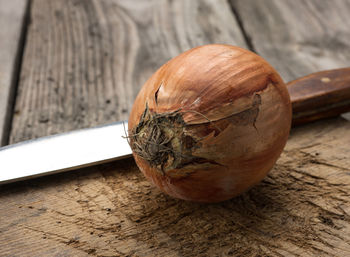 Round whole onions in brown huskon a brown wooden background, close up