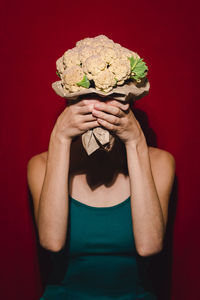 Midsection of woman holding ice cream against red background