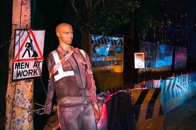 Mannequin by information sign on road at night