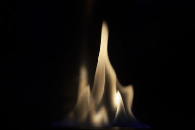 Close-up of burning candle against black background