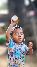 Boy holding camera while standing outdoors