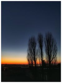 Silhouette bare trees on landscape against sky at sunset