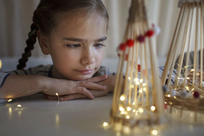 Cute girl looking at illuminated christmas ornaments