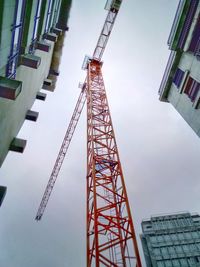 Low angle view of crane in city against sky