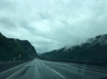 Country road against cloudy sky