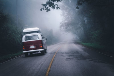 Car on road amidst trees during rainy season