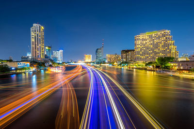 Light trails on road amidst buildings in city at night