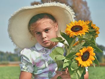 Close-up of girl with fresh sunflowers against clear blue sky