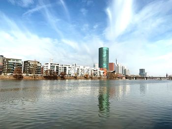 Buildings by river against sky in city