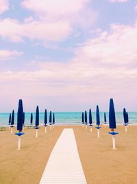 Deck chairs on beach against sky