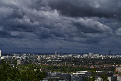 Buildings in city against storm clouds