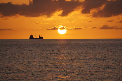 Silhouette boat in sea against sky during sunset